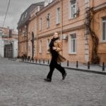 Jak włoska i francuska moda uliczna przenikają do codziennych stylizacji w polskich miastach Kobieta w płaszczu biegnie przez ulicę w stylu włoskiej mody ulicznej