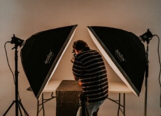 Czy fotografia to sztuka czy rzemiosło? Krótkie spojrzenie w historię sporu Fotograf przy pracy w studiu z oświetleniem softbox